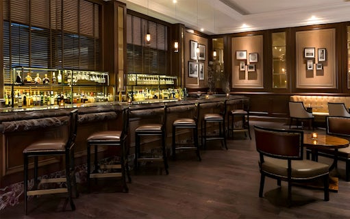 Bar area at World Cut Steakhouse, featuring a row of stools and a well-stocked bar, part of La Perle VIP experience.