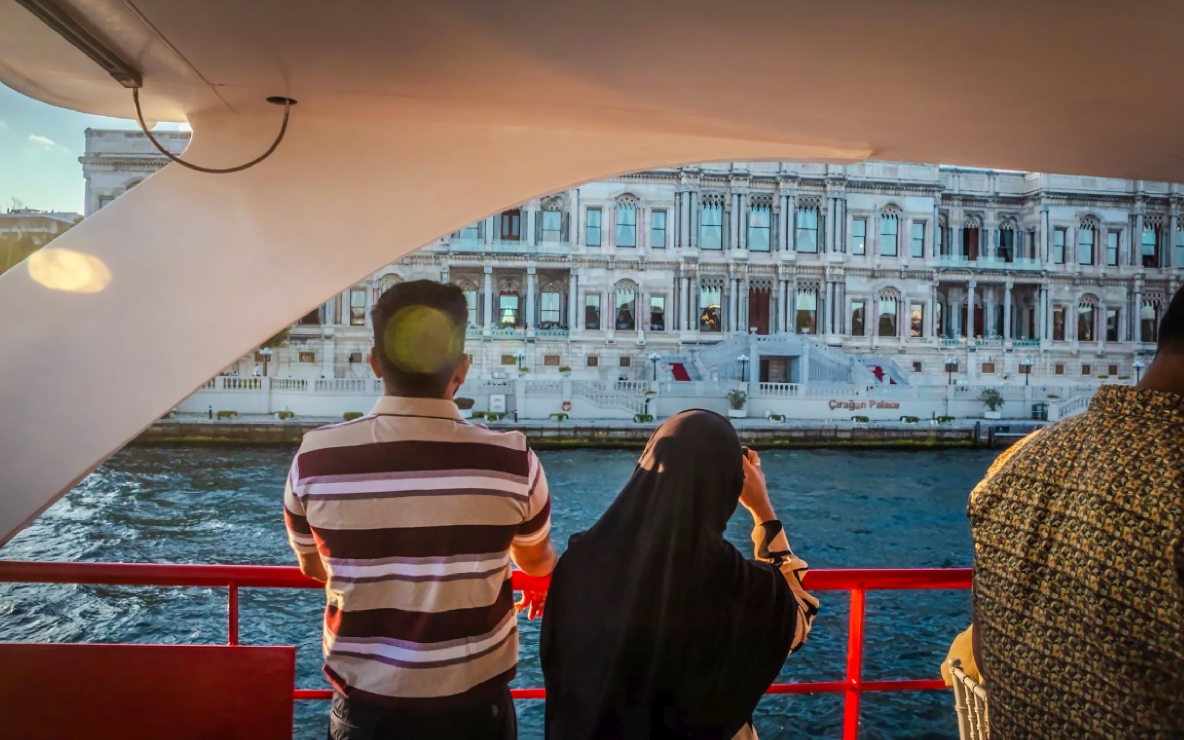 Tourists on a Bosphorus cruise viewing Dolmabahçe Palace in Istanbul.