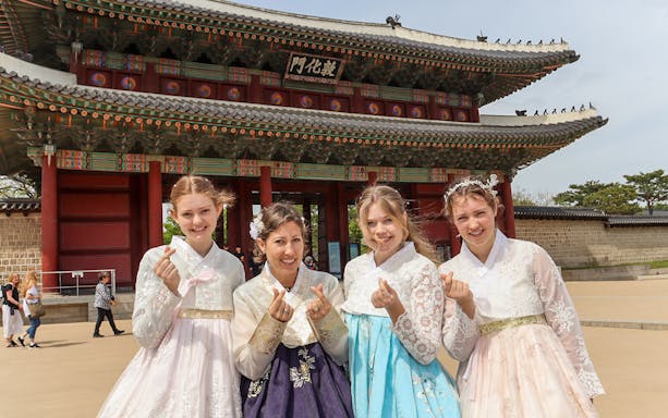 Visitors in traditional hanbok at Gyeongbokgung Palace, Seoul, during a guided tour.