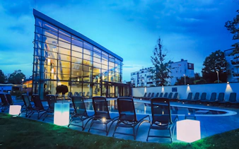 Paskal Thermal Bath in Budapest with modern glass building and poolside loungers at dusk.