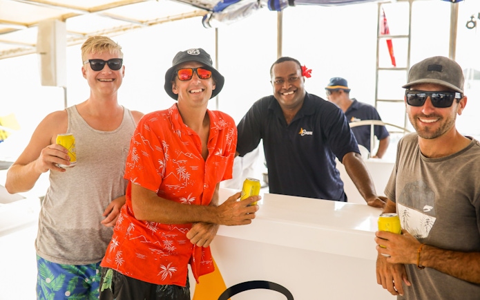 Guests enjoying drinks on the Sabre Sunset Cruise with crew members.