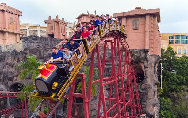 Roller coaster descending at Sunway Lagoon Theme Park with riders enjoying the thrill.