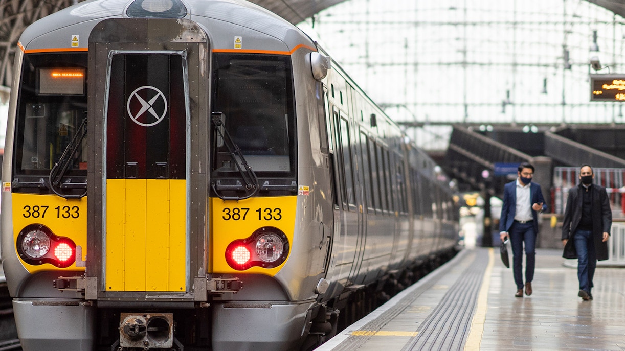 Heathrow Express train at London Paddington platform with passengers walking nearby.