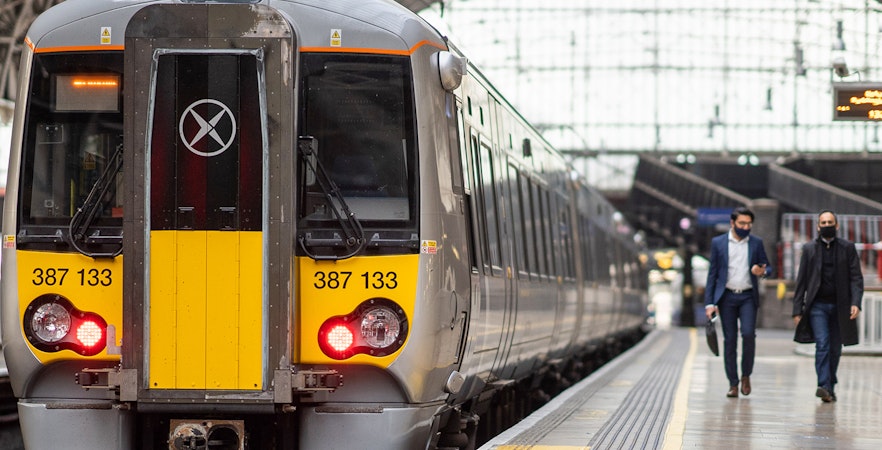 Heathrow Express train at London Paddington platform with passengers walking nearby.