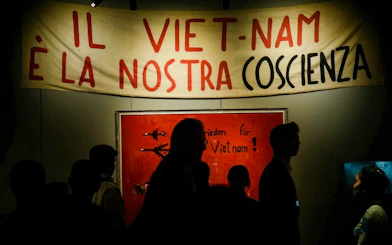 Banner with "Il Viet-Nam è la nostra coscienza" in Italian, people silhouetted below.