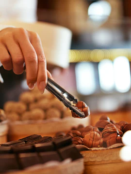 Hand selecting chocolates with tongs at Chocolate Museum Cologne.