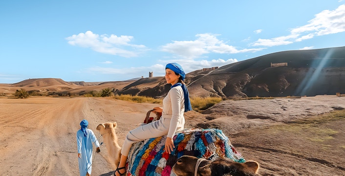 Woman riding camel in Agafay Desert, Marrakech with guide leading.