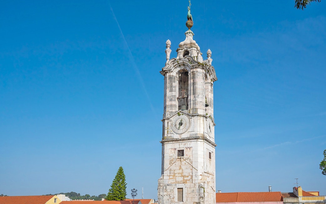 Clock tower at the National Palace of Ajuda, Lisbon, under a clear blue sky.