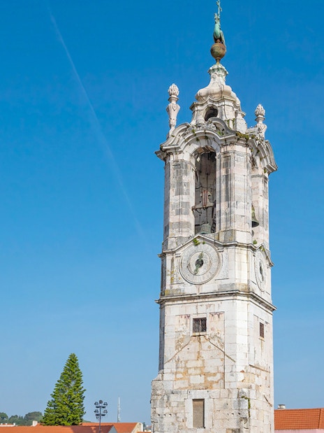 Clock tower at the National Palace of Ajuda, Lisbon, under a clear blue sky.