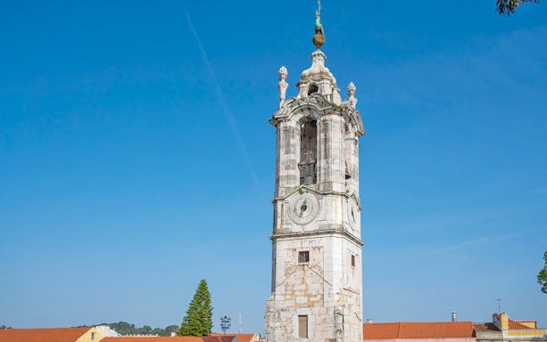 Clock tower at the National Palace of Ajuda, Lisbon, under a clear blue sky.