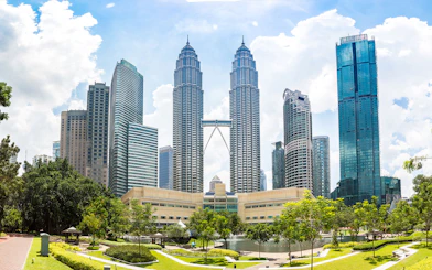 Petronas Twin Towers in Kuala Lumpur with surrounding skyscrapers and park.