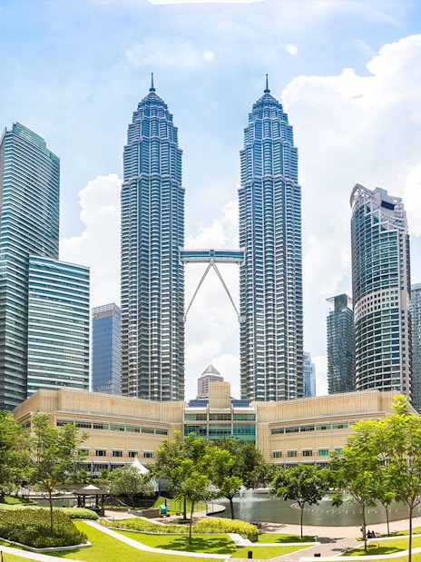 Petronas Twin Towers in Kuala Lumpur with surrounding skyscrapers and park.