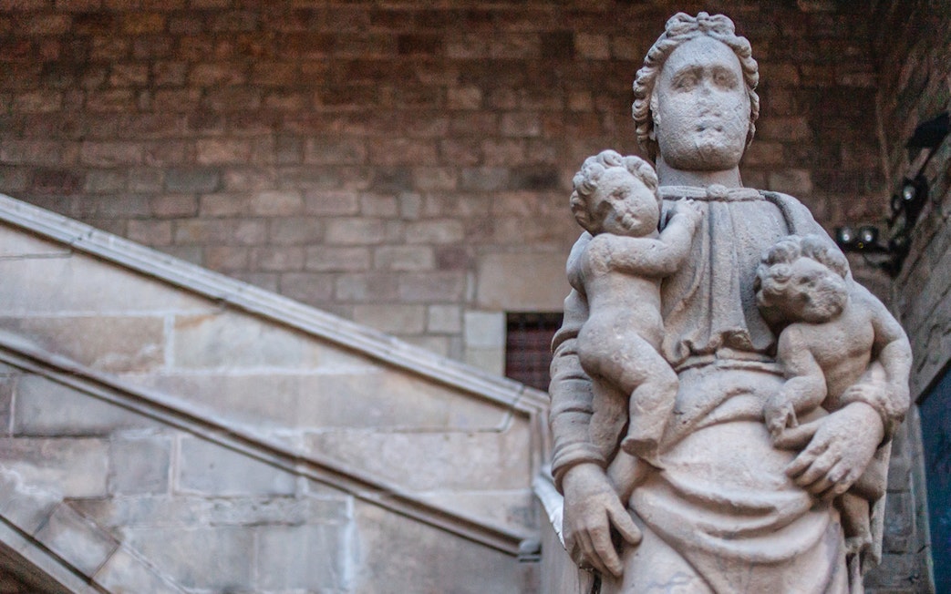 Stone statue of a woman with two children in Barcelona's Raval district.