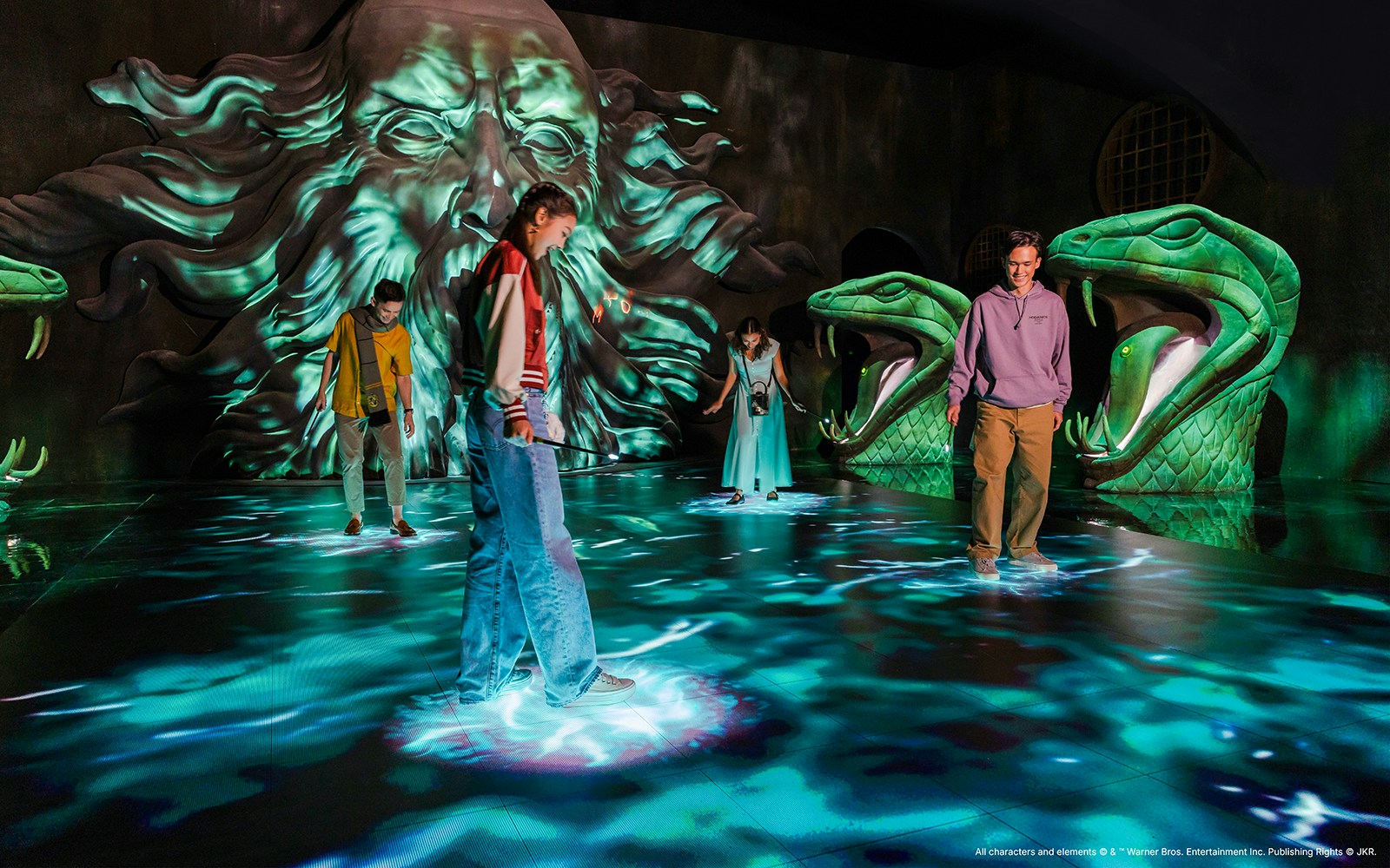 Visitors exploring Chamber of Secrets exhibit with serpent statues, Harry Potter Visions of Magic.