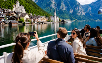Tourists on a boat enjoying views of Hallstatt village and lake, Austria.