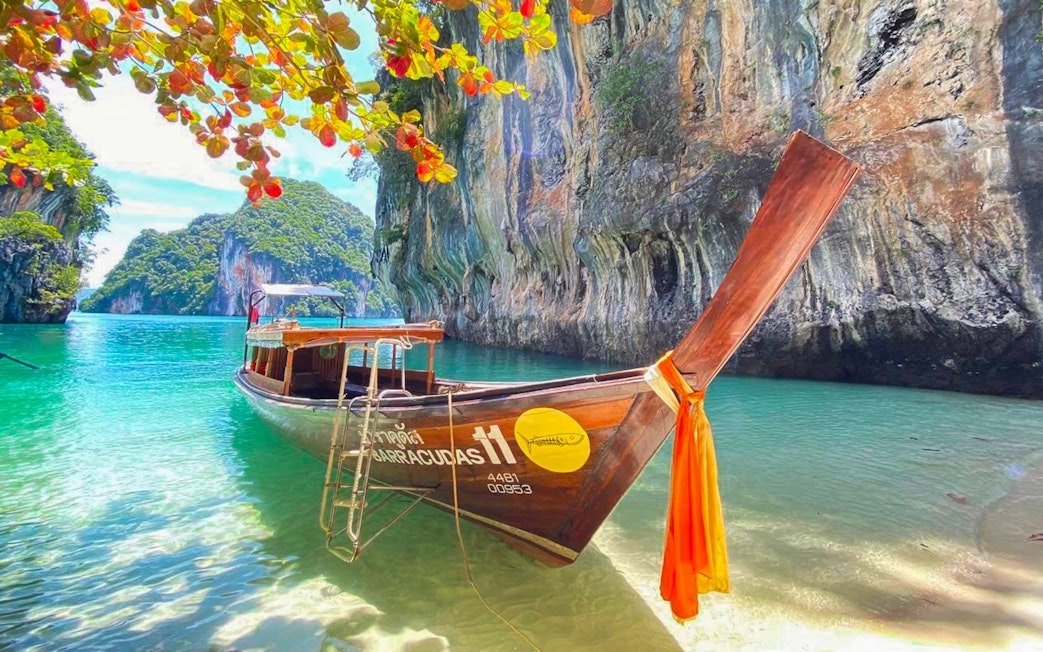 Longtail boat anchored near limestone cliffs in Krabi, Thailand, part of the 4 islands tour.