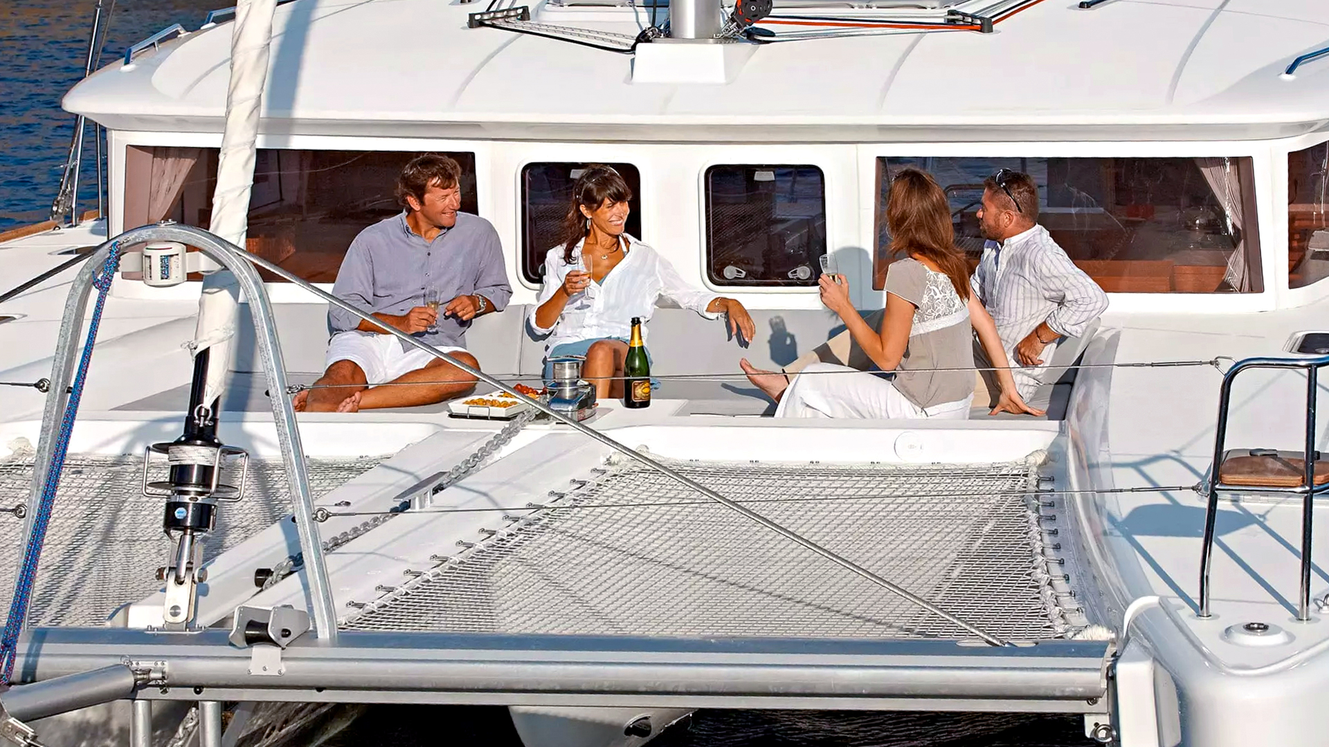 Guests relaxing on a catamaran during Santorini Luxury Cruise with drinks and snacks.