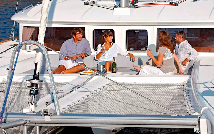 Guests relaxing on a catamaran during Santorini Luxury Cruise with drinks and snacks.
