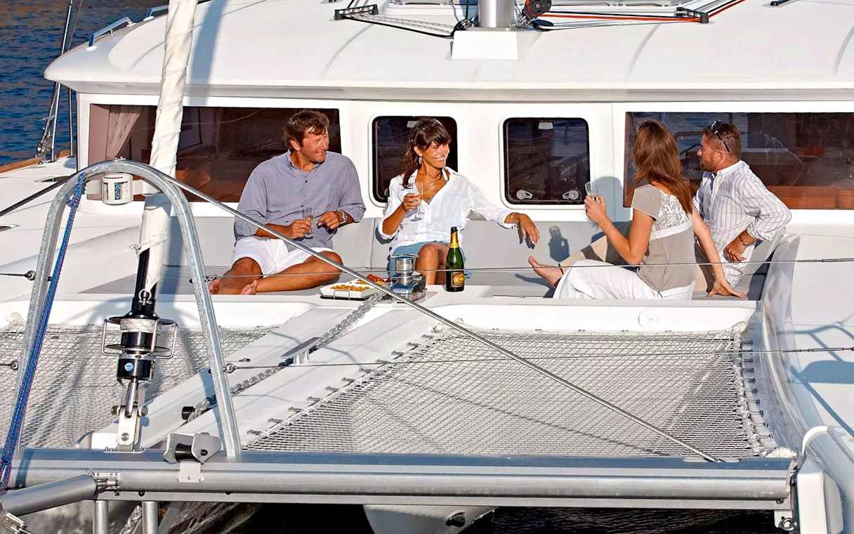 Guests relaxing on a catamaran during Santorini Luxury Cruise with drinks and snacks.