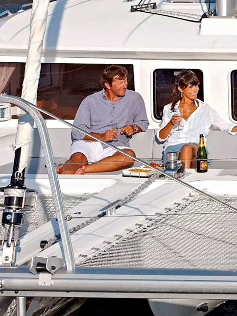 Guests relaxing on a catamaran during Santorini Luxury Cruise with drinks and snacks.
