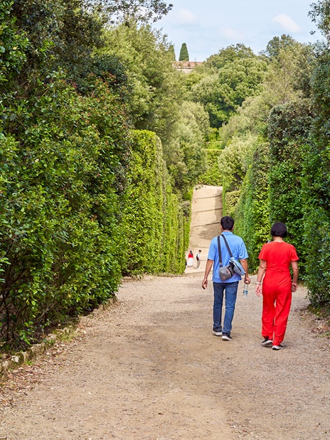 Tourists walking through lush greenery in Boboli Gardens, Florence, Italy.