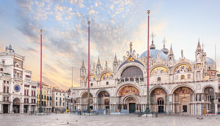St. Mark's Basilica and Clocktower in Piazza San Marco, Venice, with tourists exploring the square.