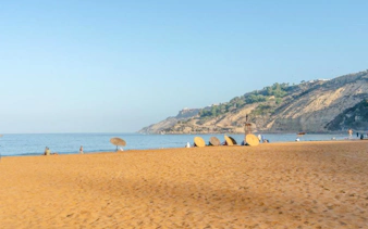 Sandy beach with umbrellas and cliffs in Safi Region, Essaouira.