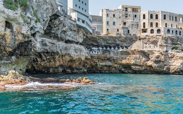 Cliffside view of Polignano a Mare with historic buildings above the Adriatic Sea.