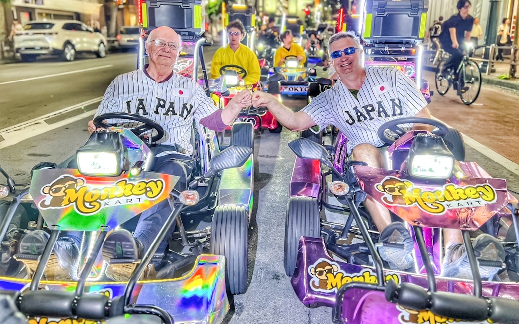 Men in Japan jerseys fist bump on Tokyo go-kart tour.