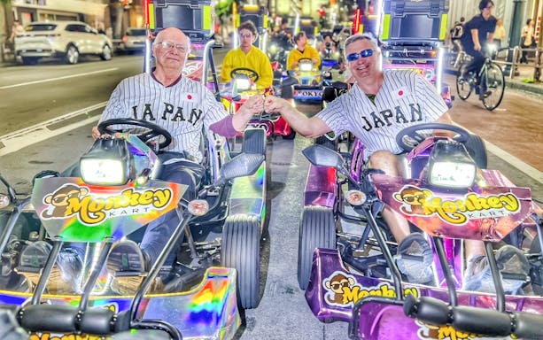 Men in Japan jerseys fist bump on Tokyo go-kart tour.