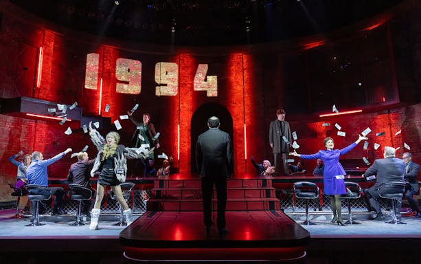 Stage performance with actors in 1994 setting, money flying, related to Patriots theme.