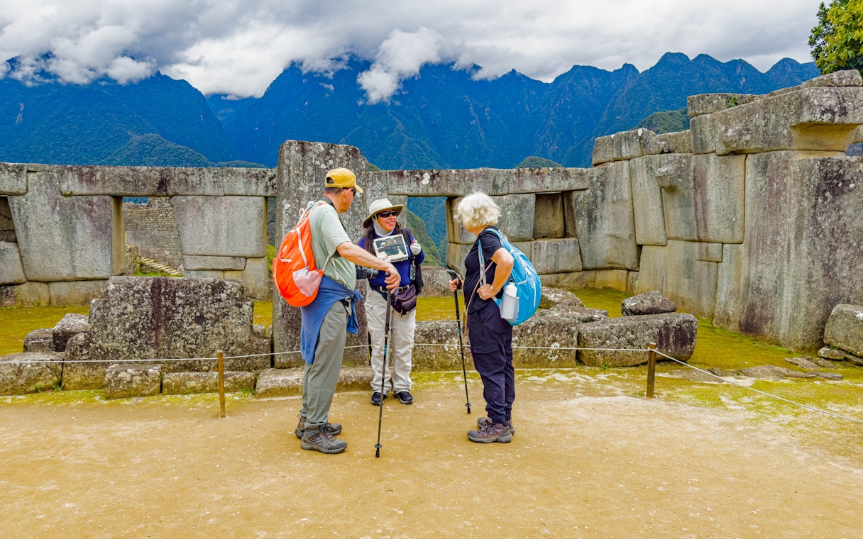 Guide with tourists at the Temple of the Three Windows, Machu Picchu, Peru.