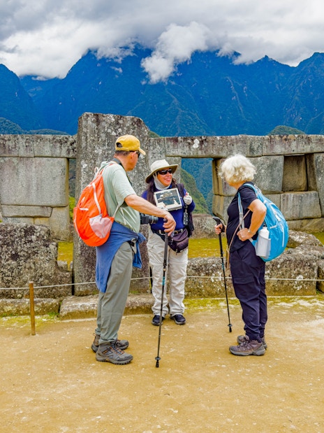 Guide with tourists at the Temple of the Three Windows, Machu Picchu, Peru.