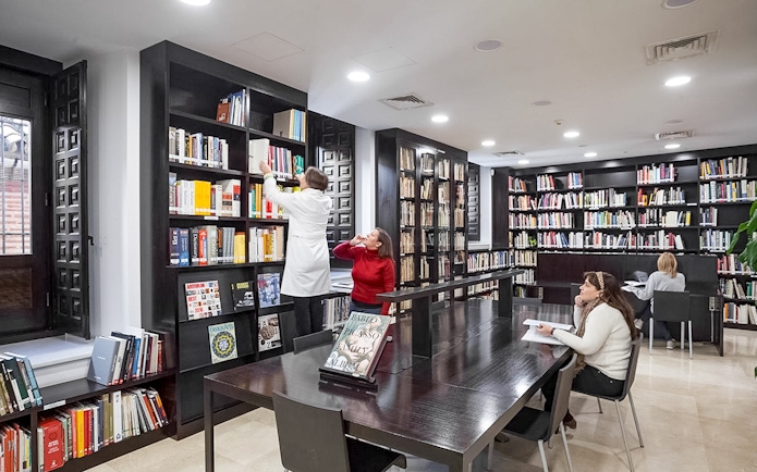Library interior of the Picasso Museum in Malaga with people reading and browsing books.
