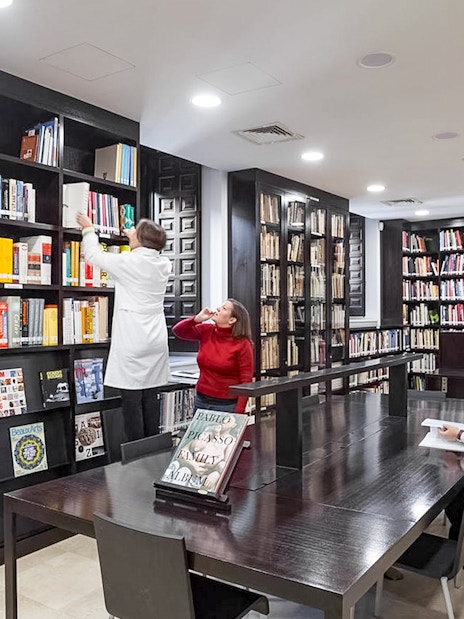Library interior of the Picasso Museum in Malaga with people reading and browsing books.