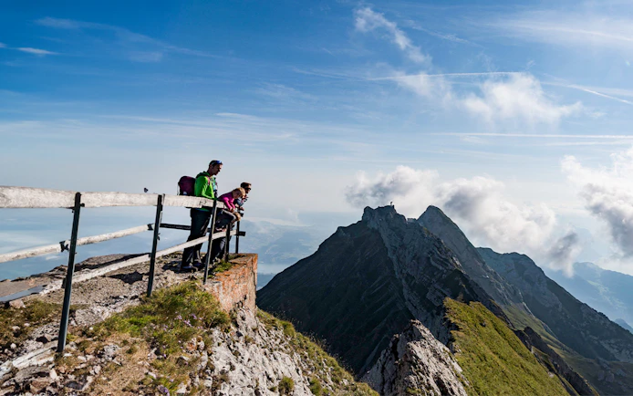 Visitors enjoying the view from Mount Pilatus summit, Lucerne, with mountain peaks in the background.