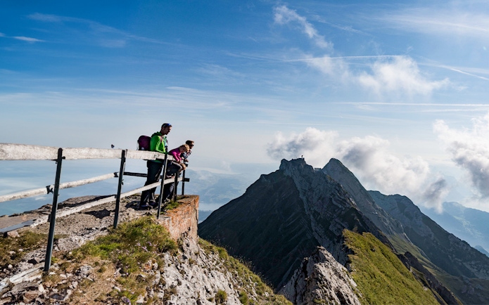 Visitors enjoying the view from Mount Pilatus summit, Lucerne, with mountain peaks in the background.