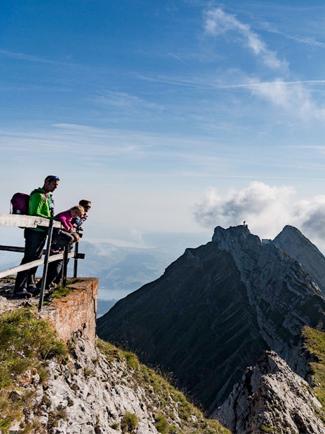 Visitors enjoying the view from Mount Pilatus summit, Lucerne, with mountain peaks in the background.