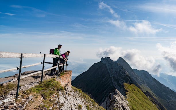 Visitors enjoying the view from Mount Pilatus summit, Lucerne, with mountain peaks in the background.