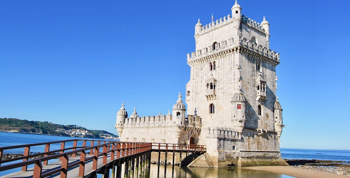 Belem Tower in Lisbon with wooden pathway over water.