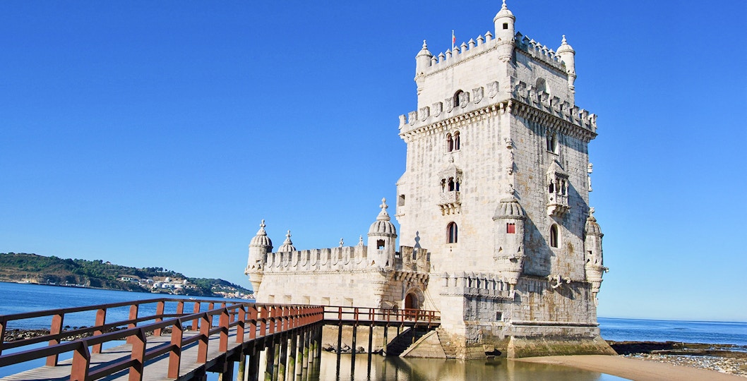 Belem Tower in Lisbon with wooden pathway over water.