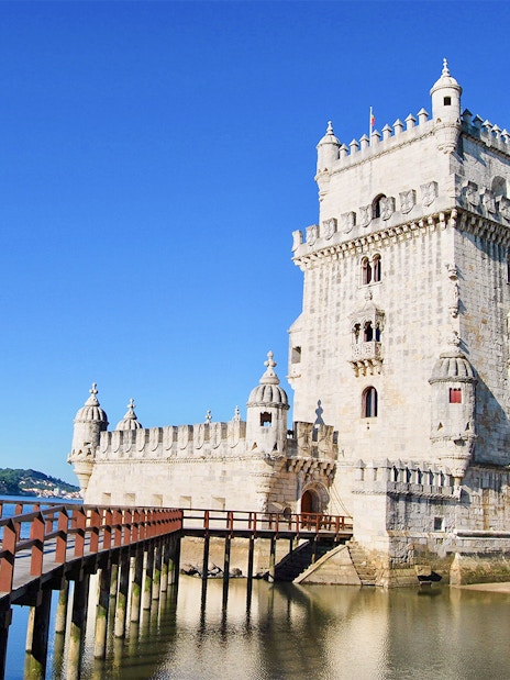 Belem Tower in Lisbon with wooden pathway over water.