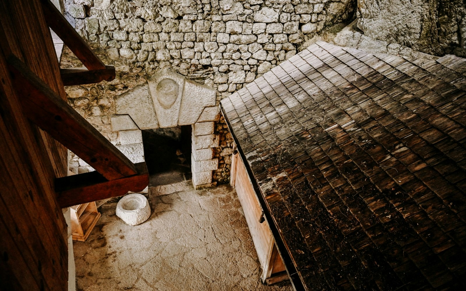 Predjama Castle interior with stone walls and wooden roof structure.