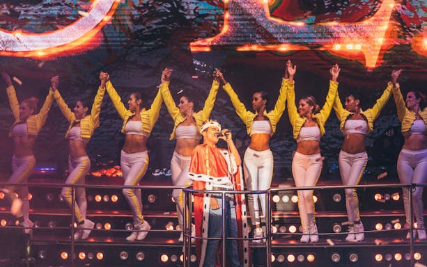 Performer in royal costume singing with dancers at Coco Bongo Show & Disco.