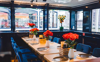 Dining setup on a boat with red roses and plates, part of a pizza cruise experience.