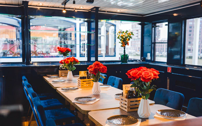Dining setup on a boat with red roses and plates, part of a pizza cruise experience.