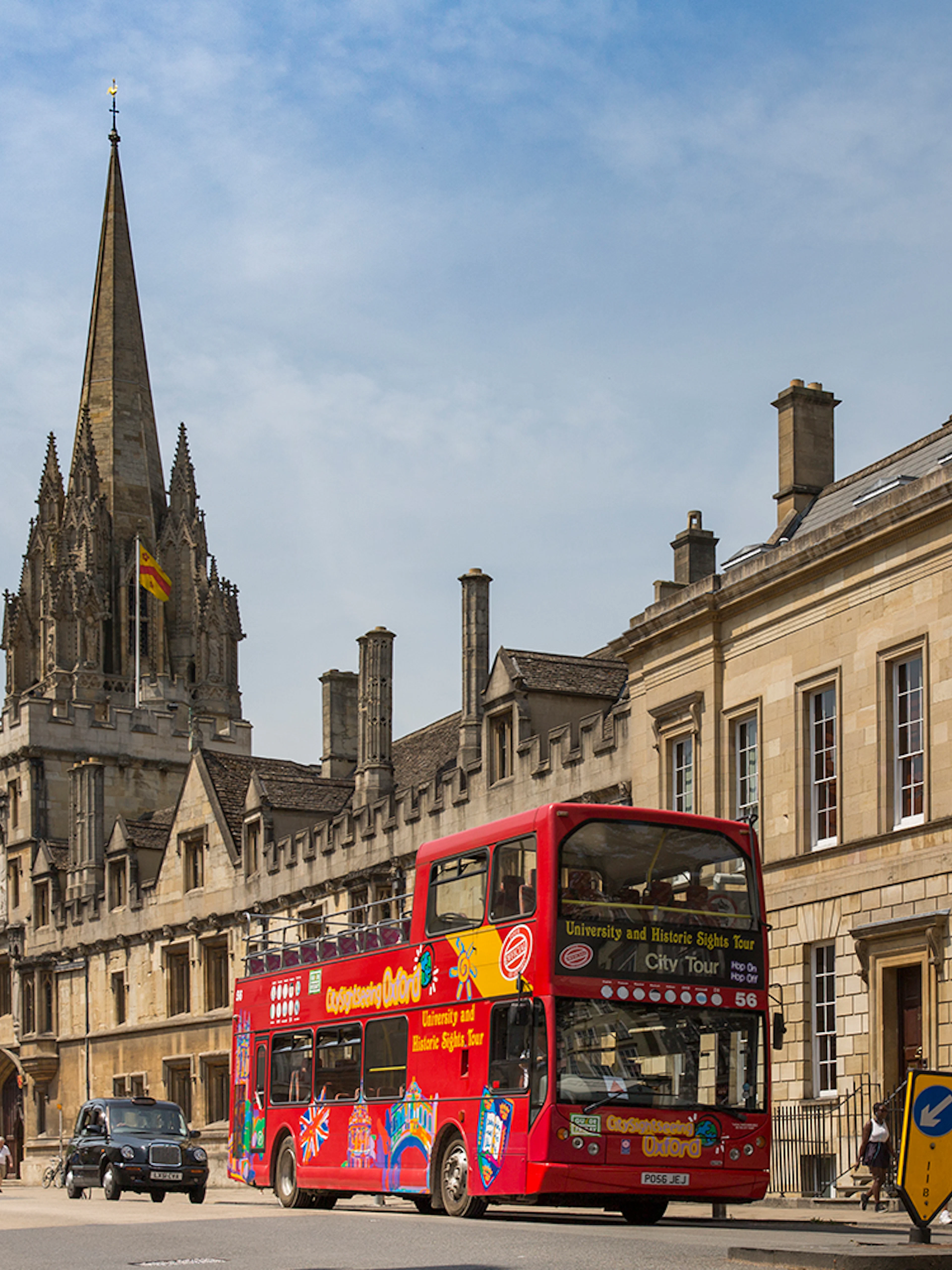Open-top tour bus passing historic Oxford architecture.