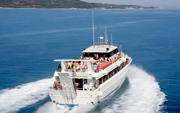 Ferry with passengers traveling from Peschici to Tremiti Islands on clear blue water.