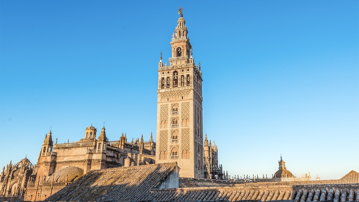 La Giralda tower in Seville, Spain, with intricate architectural details against a clear sky.