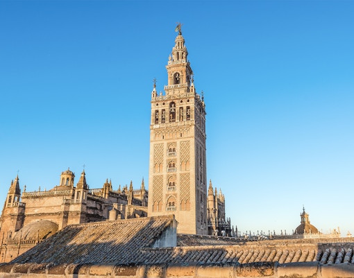 La Giralda tower in Seville, Spain, with intricate architectural details against a clear sky.